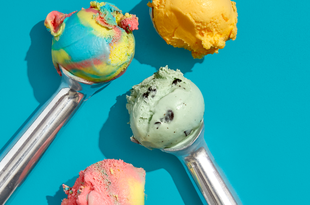 4 ice cream flavours sitting in scoops on a blue background