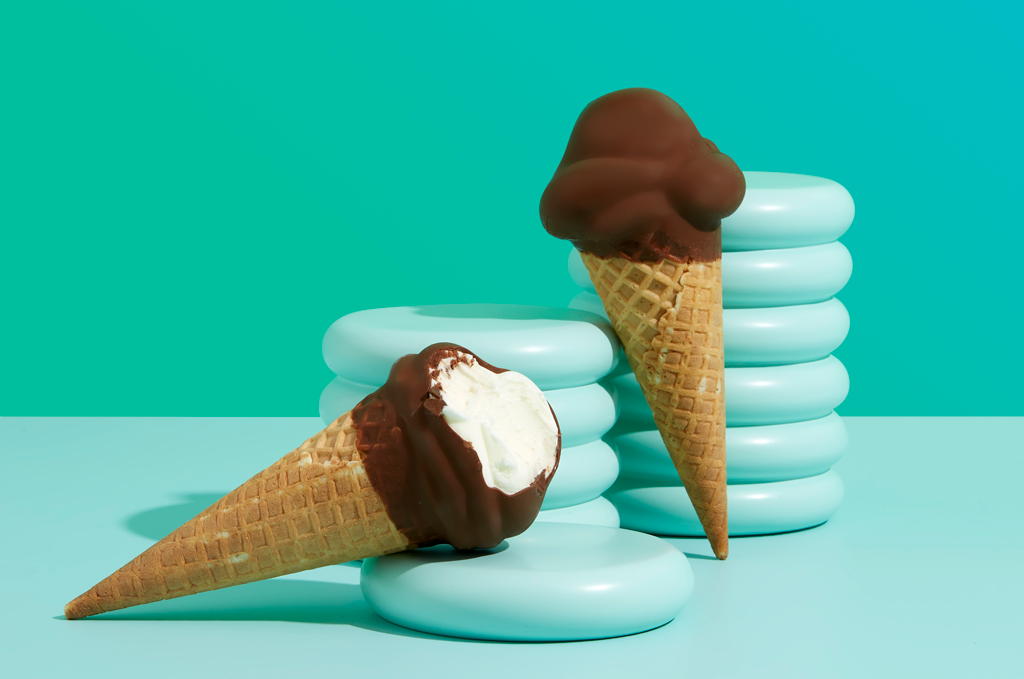 Two choc top ice cream cones on a green background