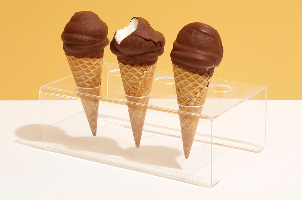 Three choc top cones standing in a plastic holder against a yellow background
